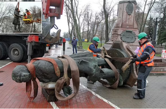 Workers remove a statue from its pedestal